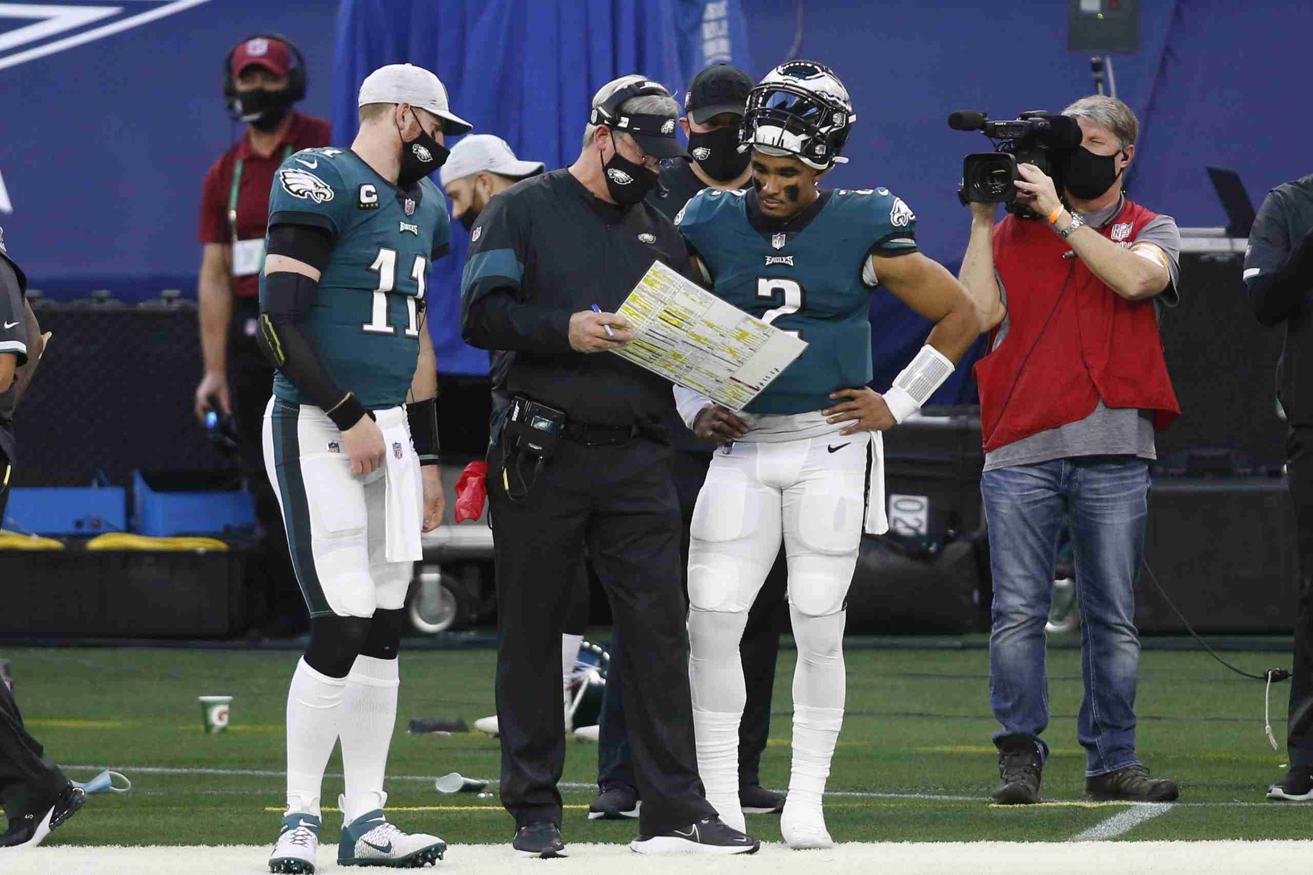 Dec 27, 2020; Arlington, Texas, USA; Philadelphia Eagles quarterbacks Carson Wentz (11) and Jalen Hurts (2) talk with head coach Doug Pederson (C) during a timeout against the Dallas Cowboys in the second quarter at AT&T Stadium. Mandatory Credit: Tim Heitman-USA TODAY Sports